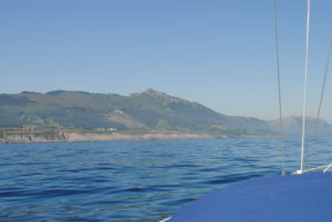 Steep green mountains drop into the sea.